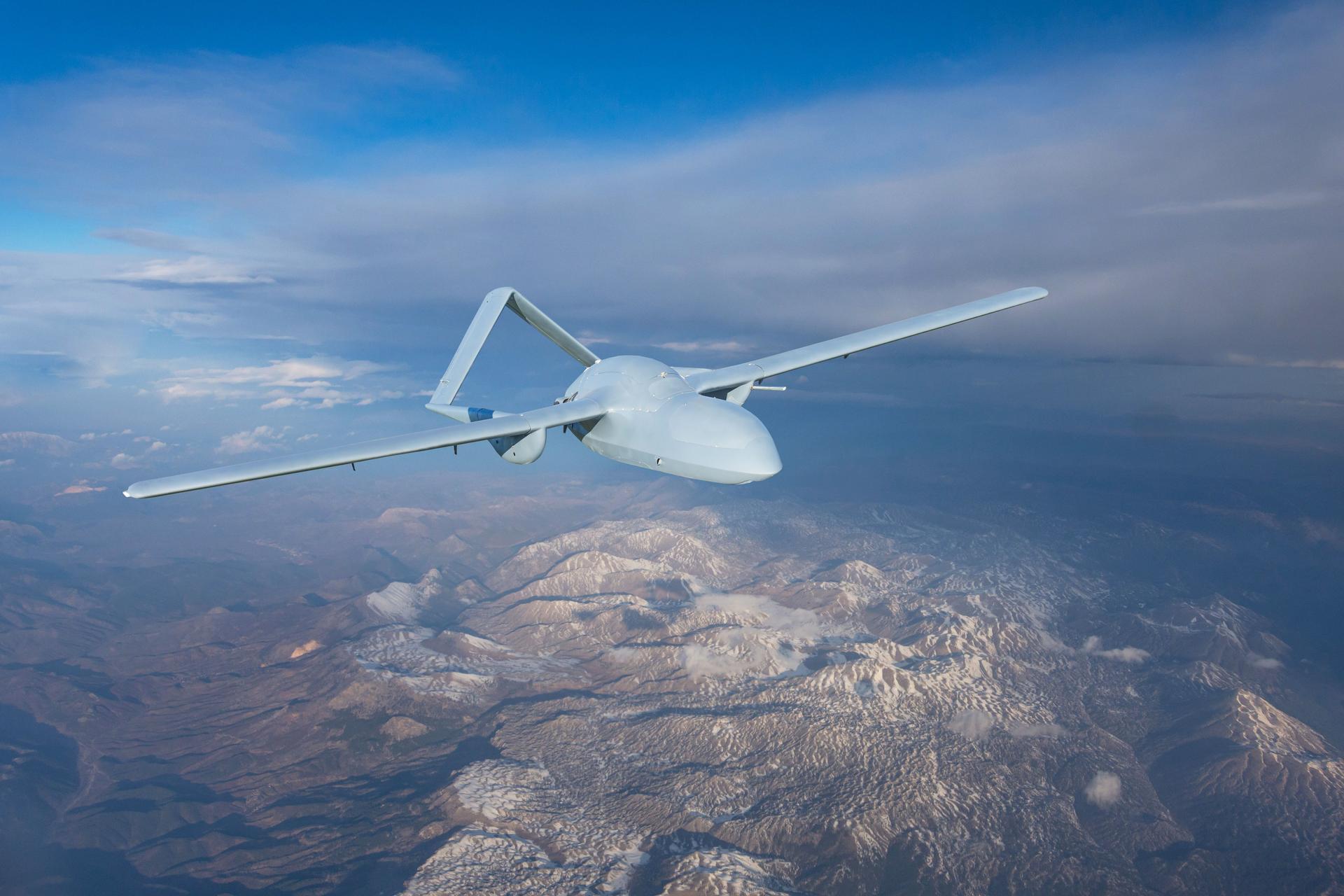 Drone militare senza pilota uav che vola in aria, volo di ricognizione sul territorio sopra le montagne innevate colline rilievo.