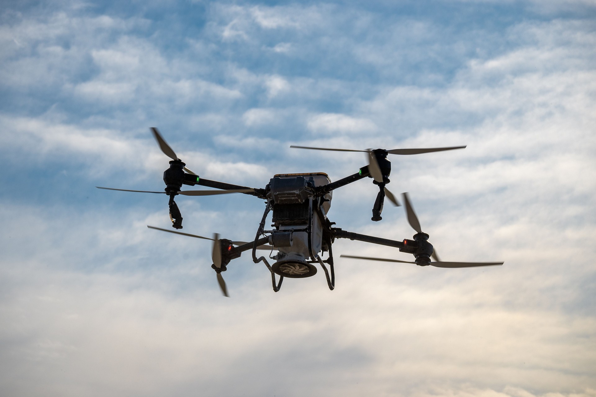 Large agricultural drone in flight, fertilizing a sown field.